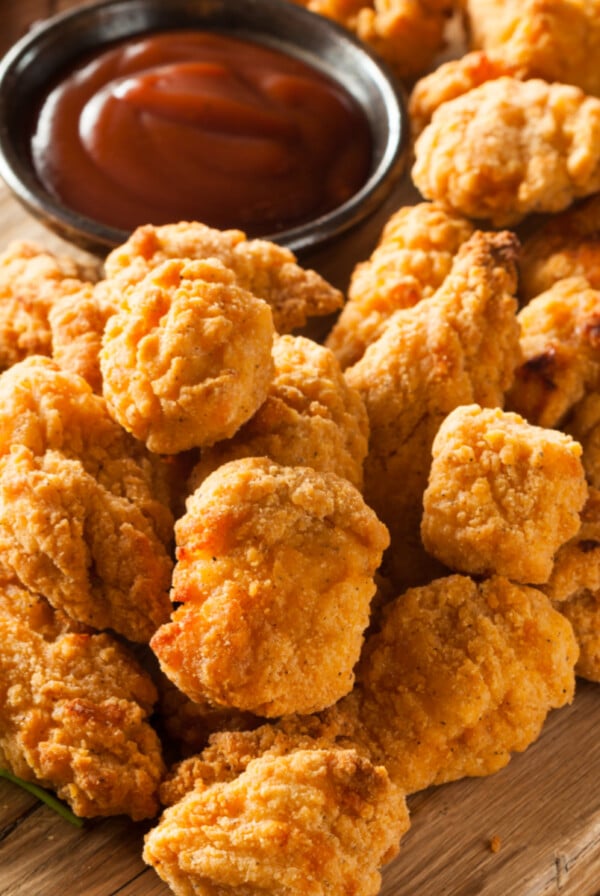 Crispy Air Fryer Chicken Bites on a cutting board with a side of barbecue sauce for serving.