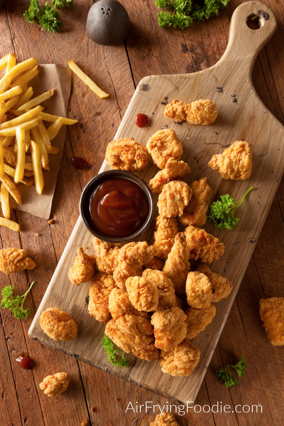 Crispy Air Fryer Chicken Bites on a cutting board served with ketchup.