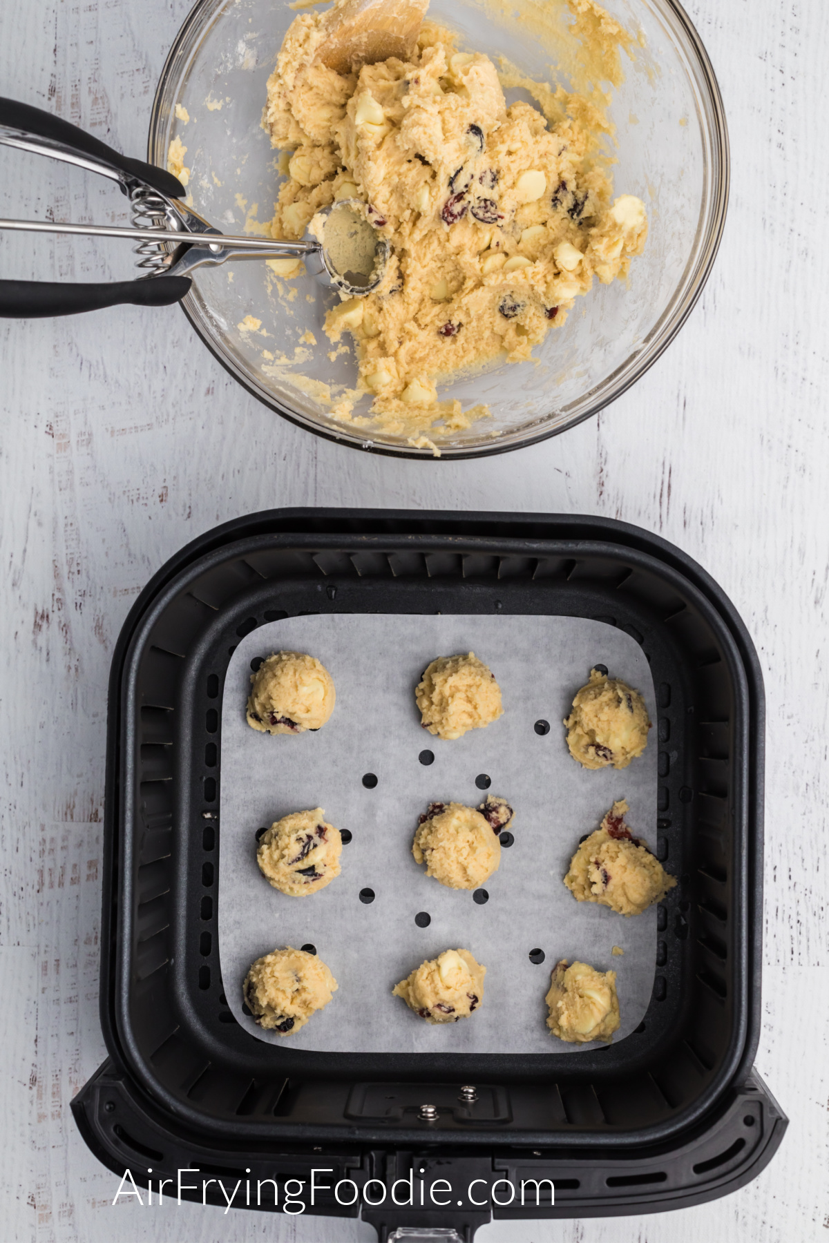 Cookie dough scooped onto parchment paper in the air fryer basket.