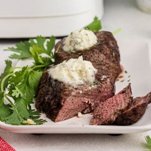 Close up of juicy steak cut and topped with melting blue cheese butter on top.