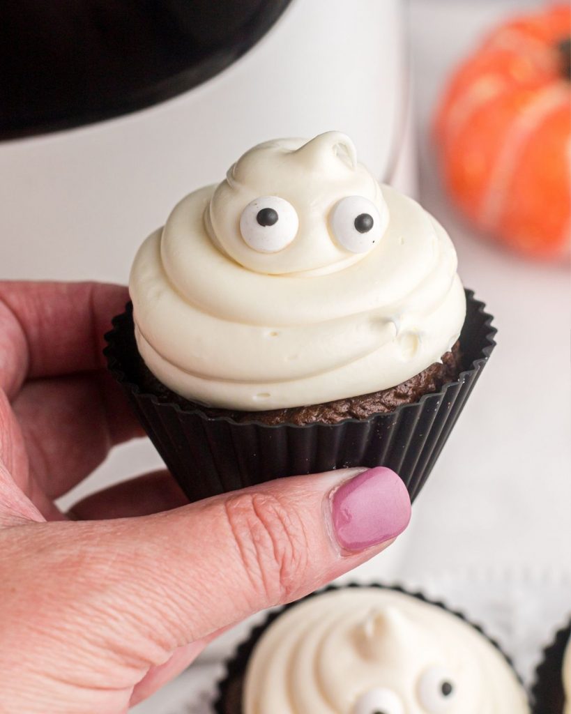 Close up photo of a ghost cupcake showing the eyes and mound of frosting. 