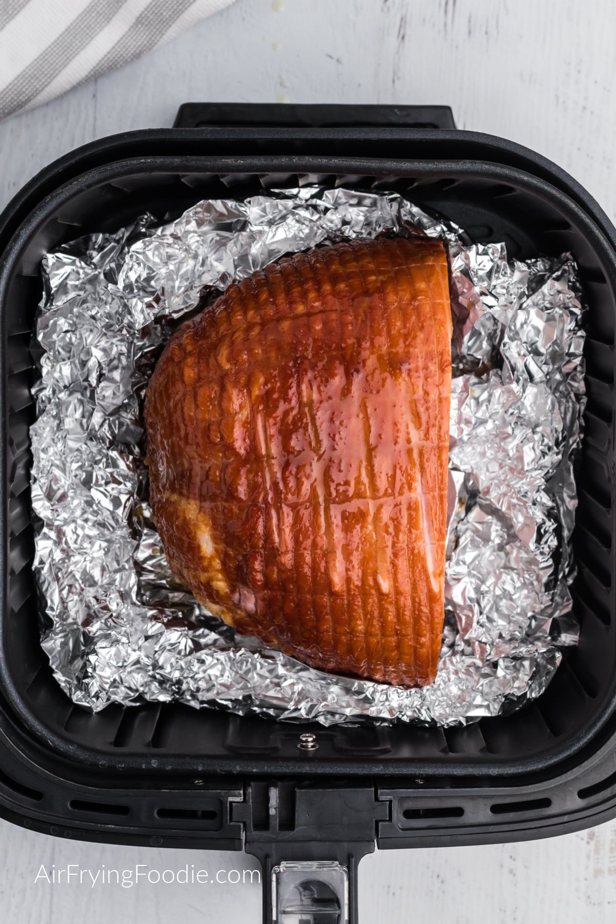 ham in air fryer basket laying on foil, ready to be served.