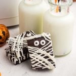 Brownies frosted to look like mummies with candy eyes, leaning up against little bottles of milk