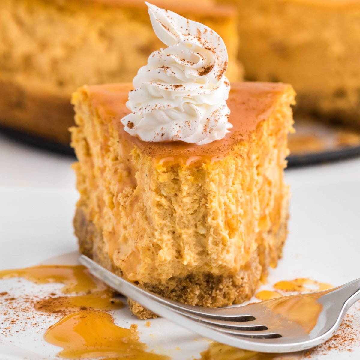 Air Fryer pumpkin cheesecake slice on a white plate with a bite missing.