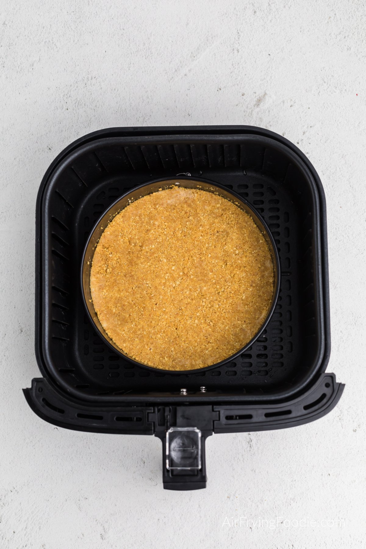 graham cracker crust in the air fryer basket ready to cook