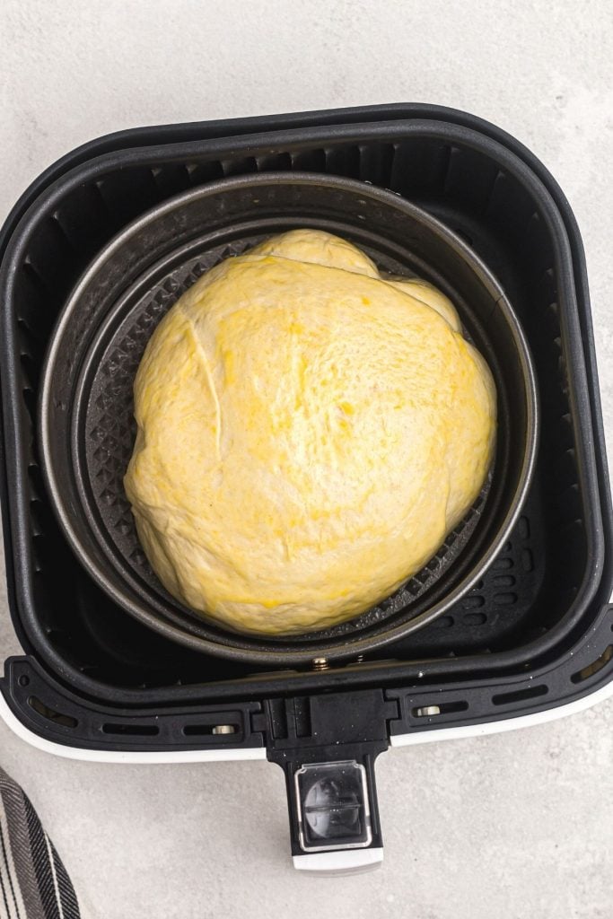 Uncooked risen dough in a springform pan before being cooked in the air fryer basket. 
