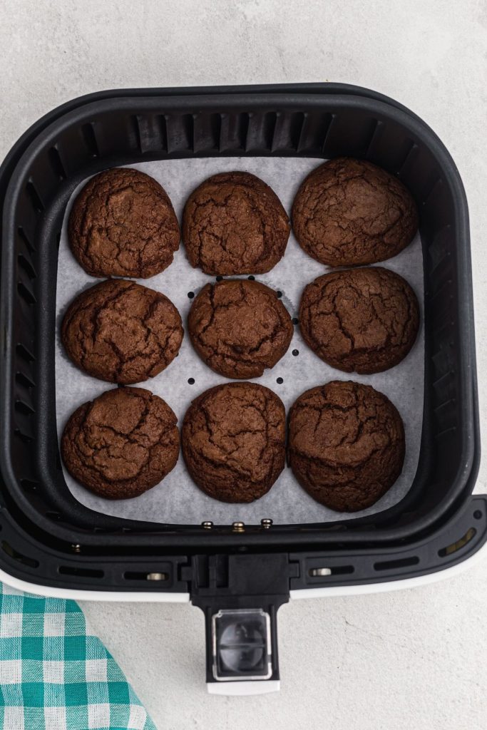 Nine chocolate cookies in the air fryer basket after being cooked. 