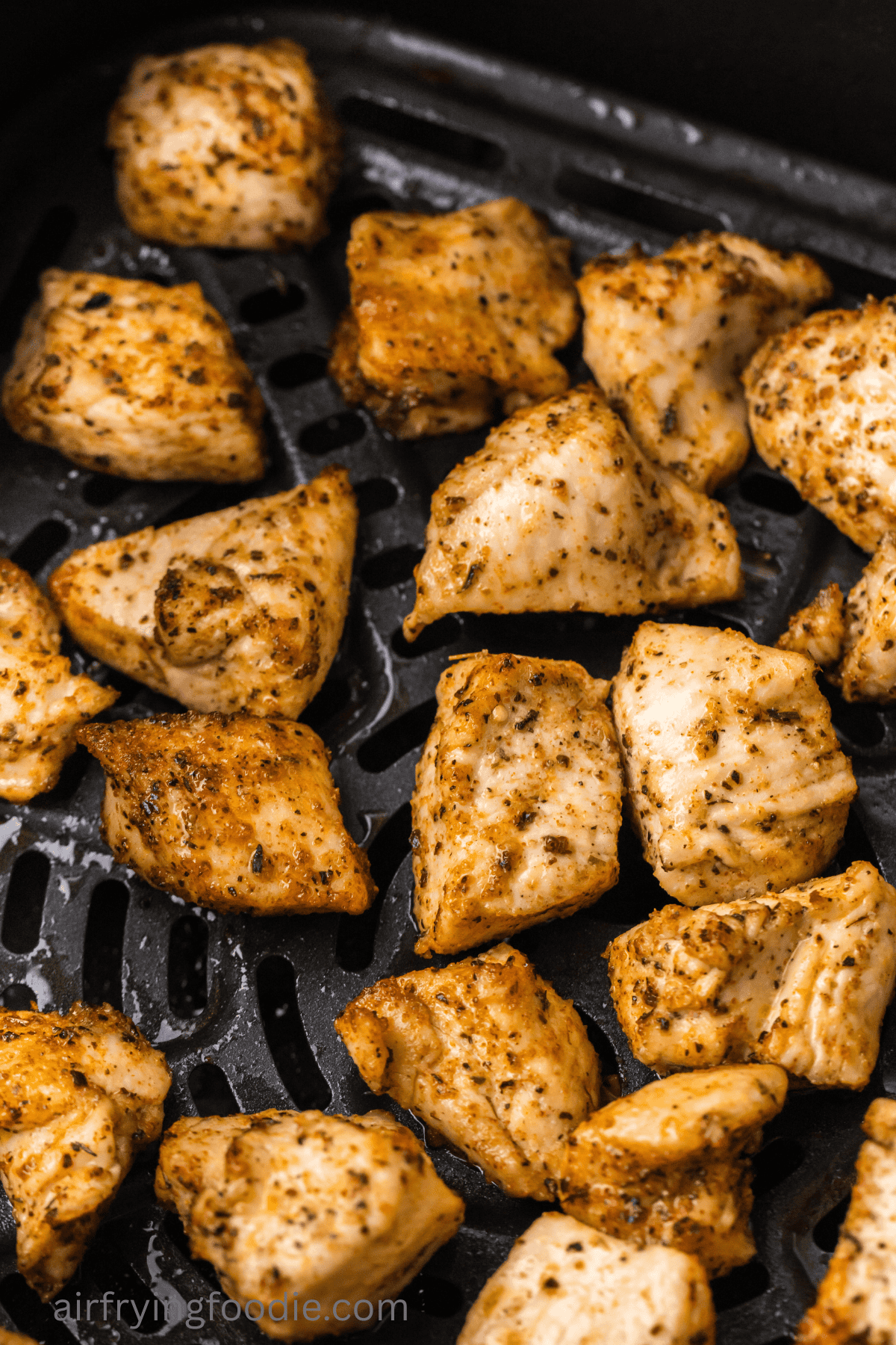 Juicy chicken bites in air fryer basket. 