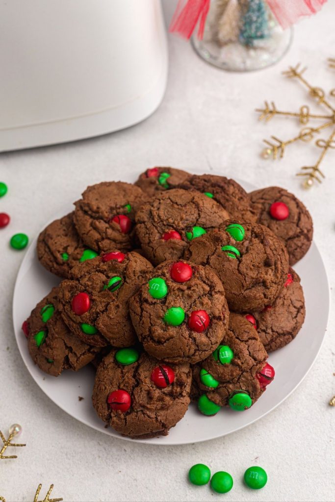 Fudgy brownie cookies with red and green candies baked in, served on a white plate. 
