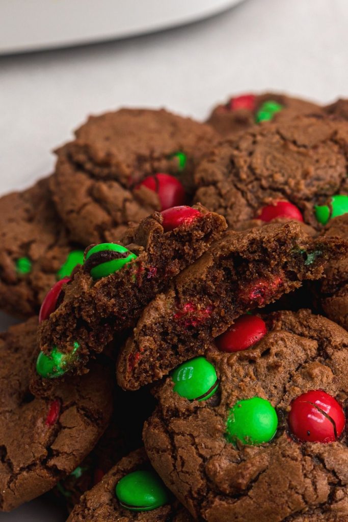 Brownie cookies with Christmas candies baked in, one broken in half. 