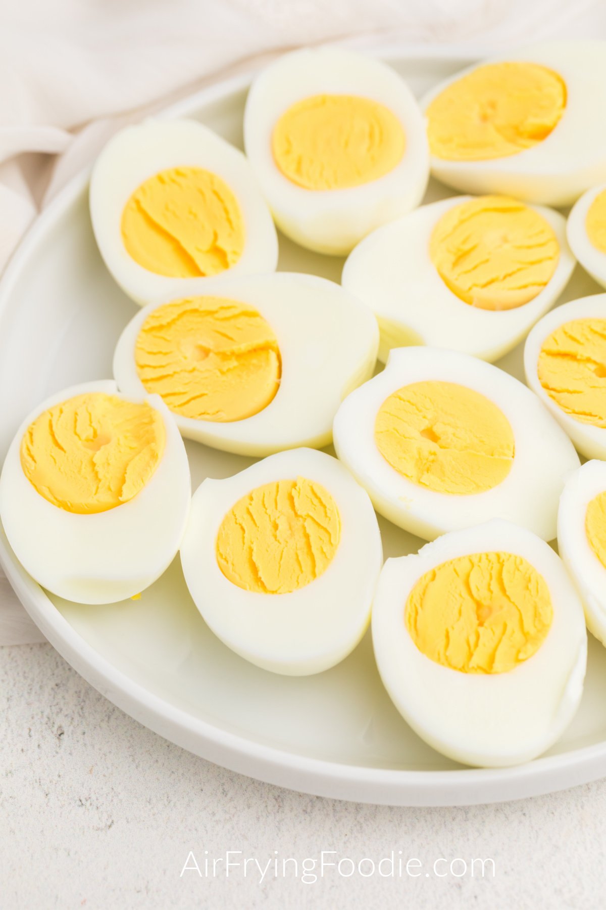 Hard boiled eggs made in the air fryer, sliced in half and served on a white plate. 