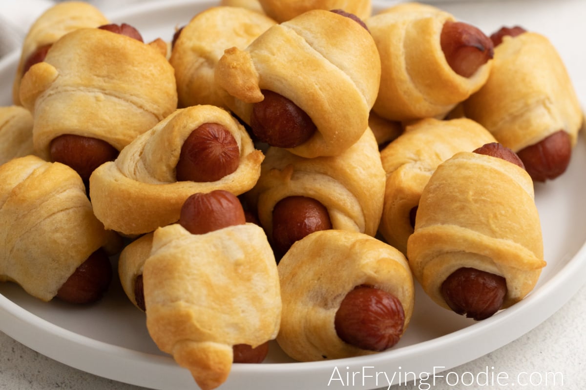 Close up photo of air fryer pigs in a blanket on a white plate. 