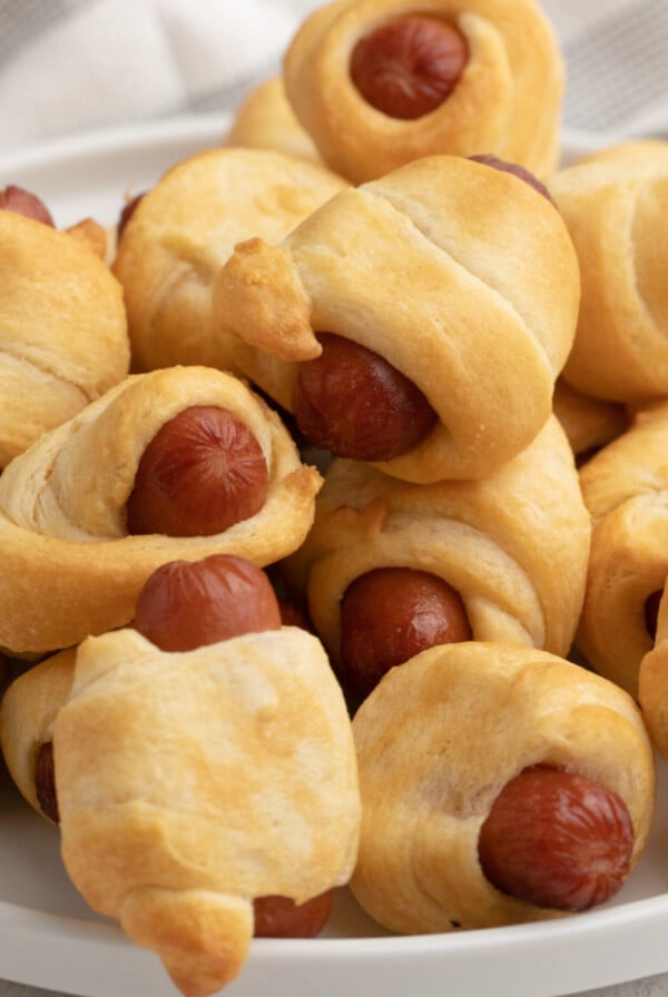 Close up photo of air fryer pigs in a blanket on a white plate ready to be served.