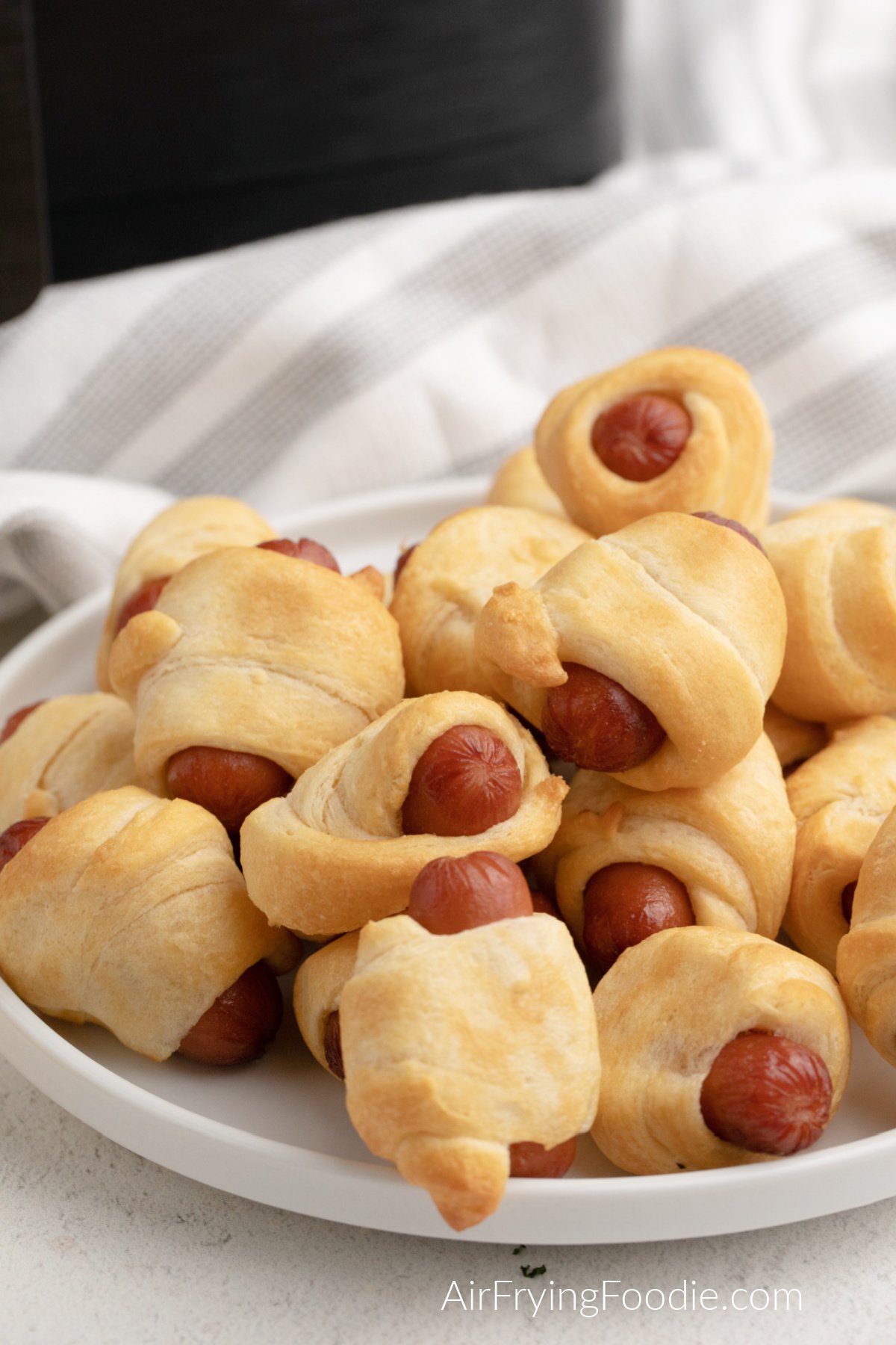 Pigs in a Blanket made in the air fryer with the air fryer in the background. 