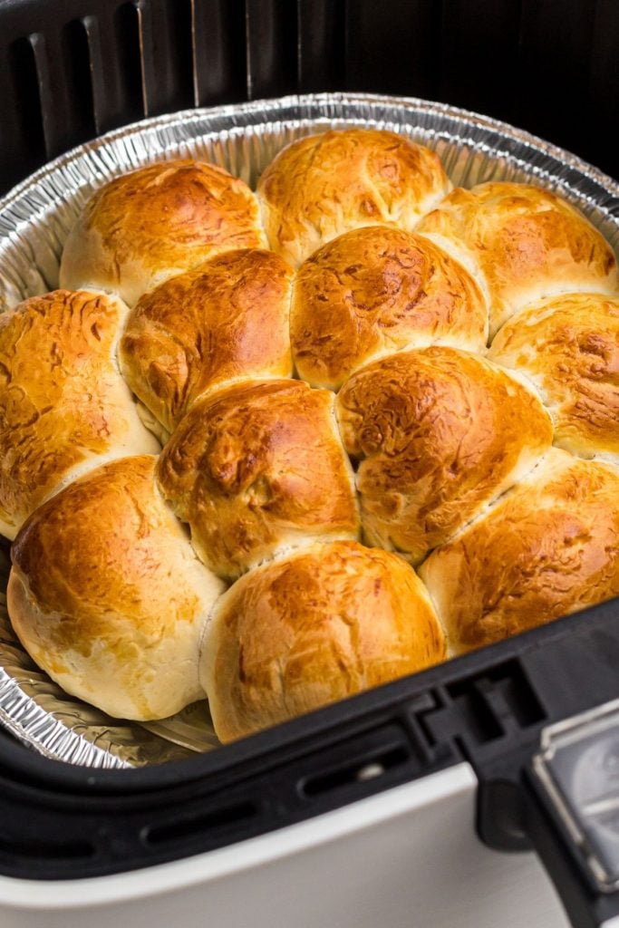 Close up photo of golden rolls in an air fryer basket after being cooked