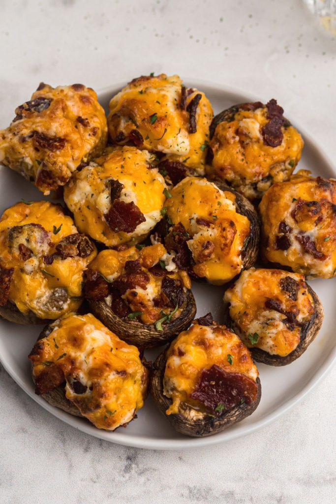 Close up photo of cooked stuffed mushrooms with melted cheese and crumbled bacon. 