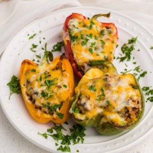 Stuffed Peppers made in the air fryer and topped with cheese and parsley and served on a white plate.
