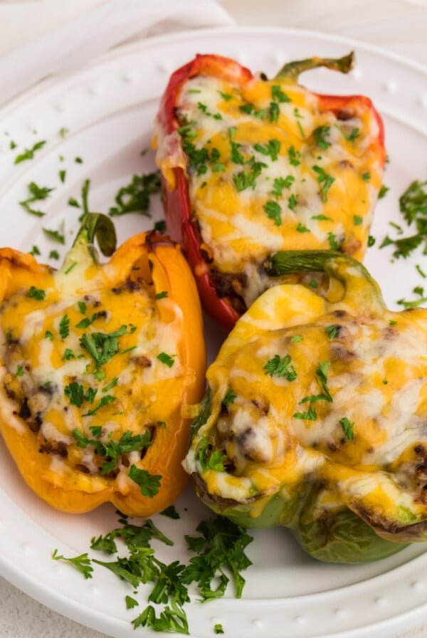 Stuffed Peppers made in the air fryer and topped with cheese and parsley and served on a white plate.