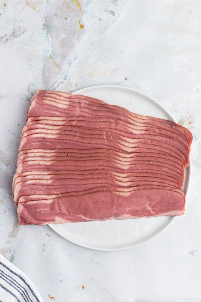 Package of turkey bacon before being cooked, on a white plate. 