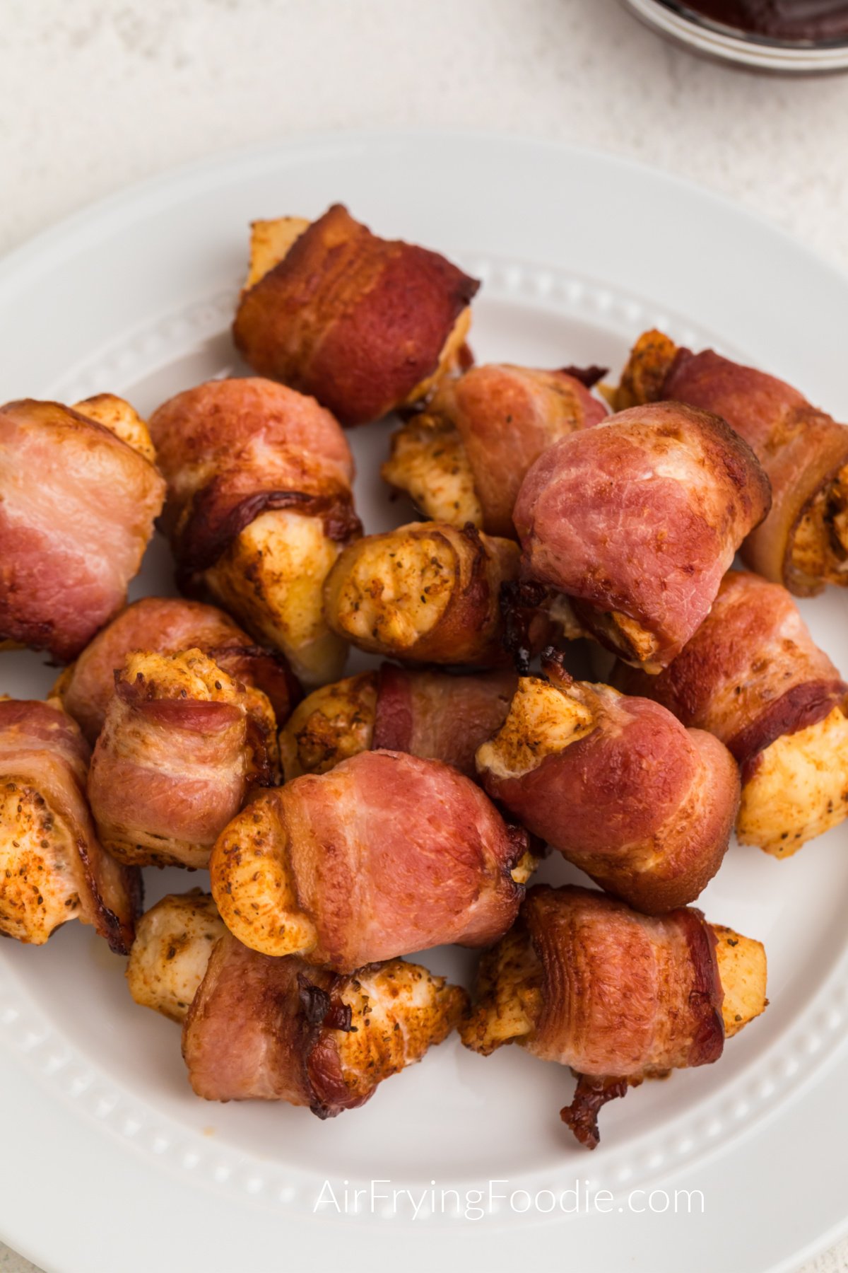 Bacon wrapped chicken bites on a white plate ready to serve. 