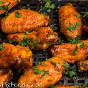 chicken wings in the basket of the air fryer topped with fresh parsley.