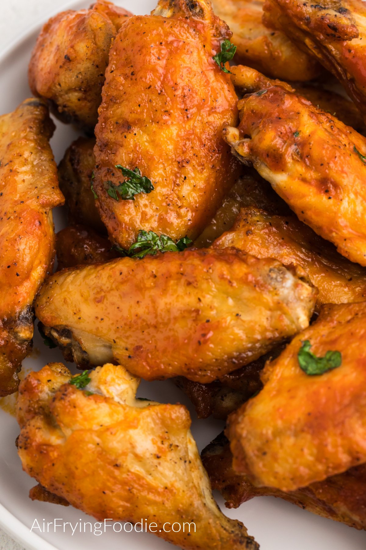 Closed up of seasoned crispy air fryer chicken wings on a white plate ready to serve.