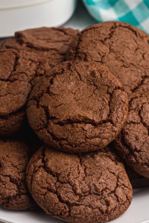 Gooey chocolate cookies on a white plate in front of an air fryer.