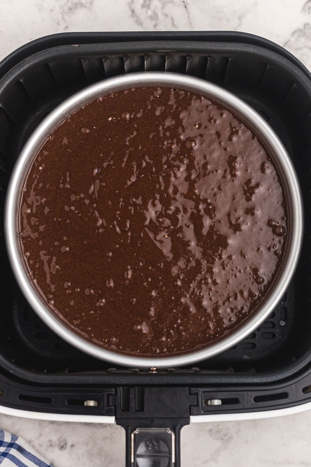 Uncooked cake mix in pan, in an air fryer basket.