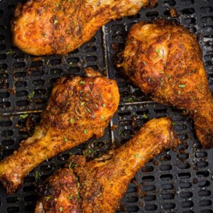 Crispy chicken drumsticks in the air fryer basket.