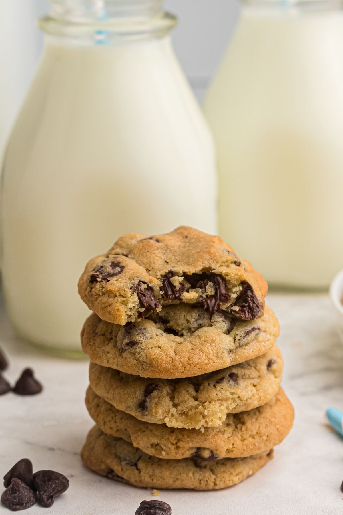 A stack of air fryer chocolate chip cookies in front of a bottle of milk.