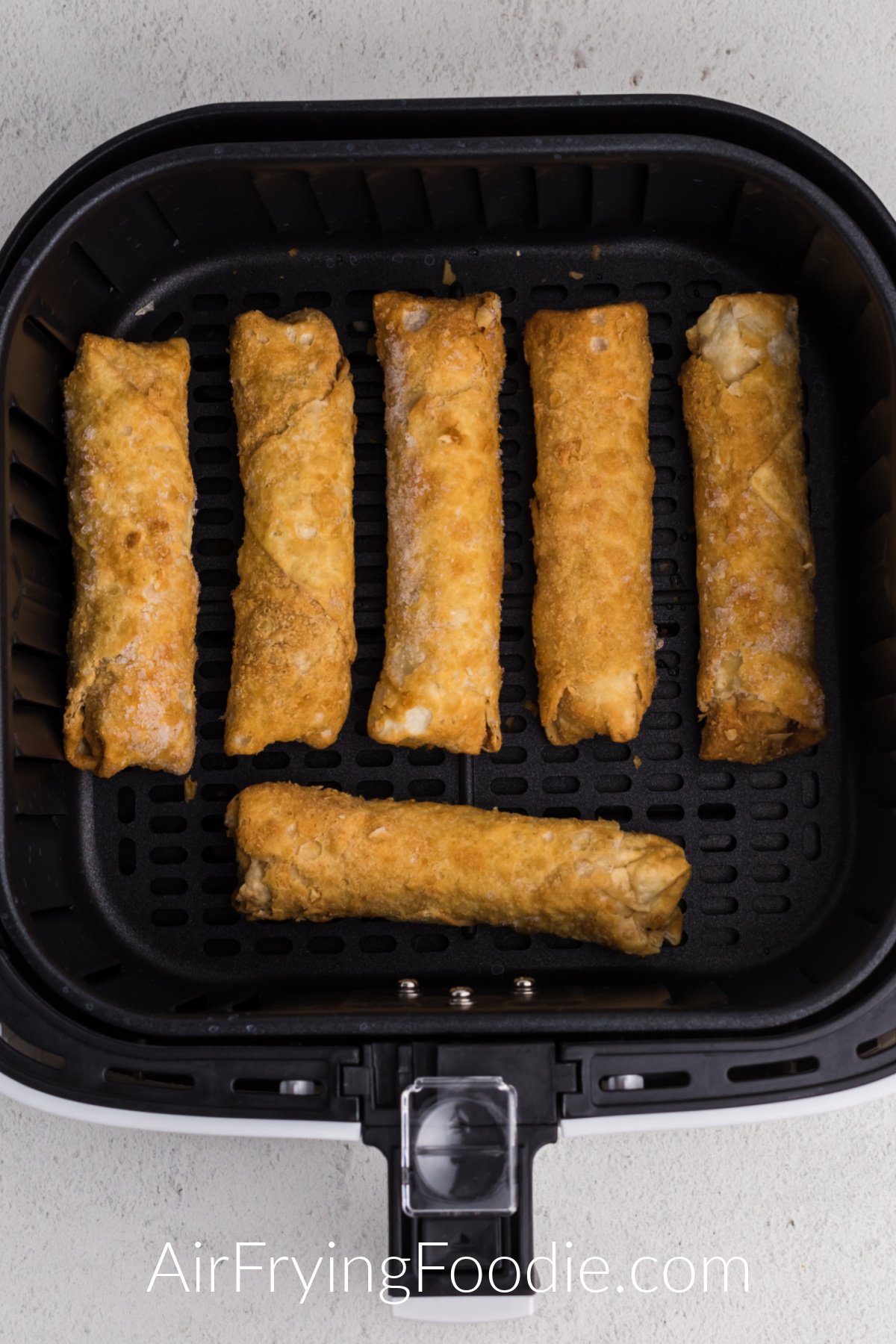 frozen egg rolls in the basket of the air fryer.