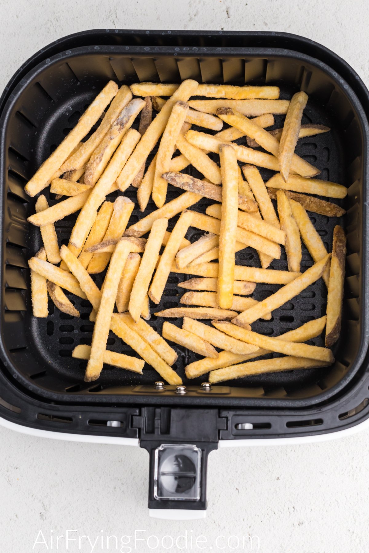 frozen fries in the basket of the air fryer.