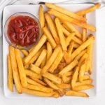 french fries on a white plate with a side of ketchup.