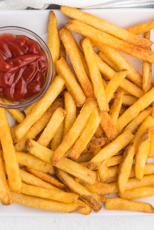 french fries on a white plate with a side of ketchup.