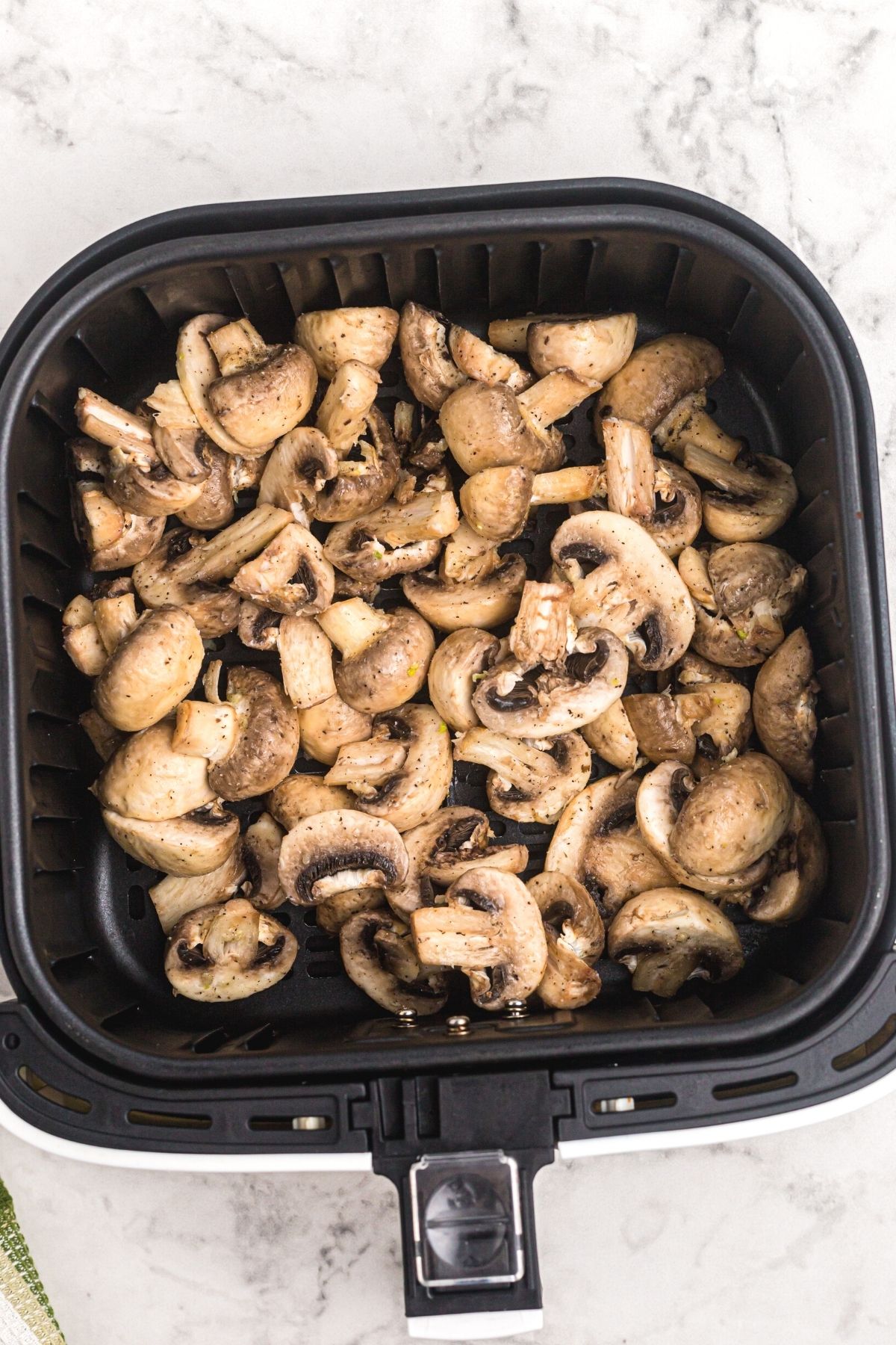 Mushrooms tossed with butter and seasonings in the air fryer basket before being cooked