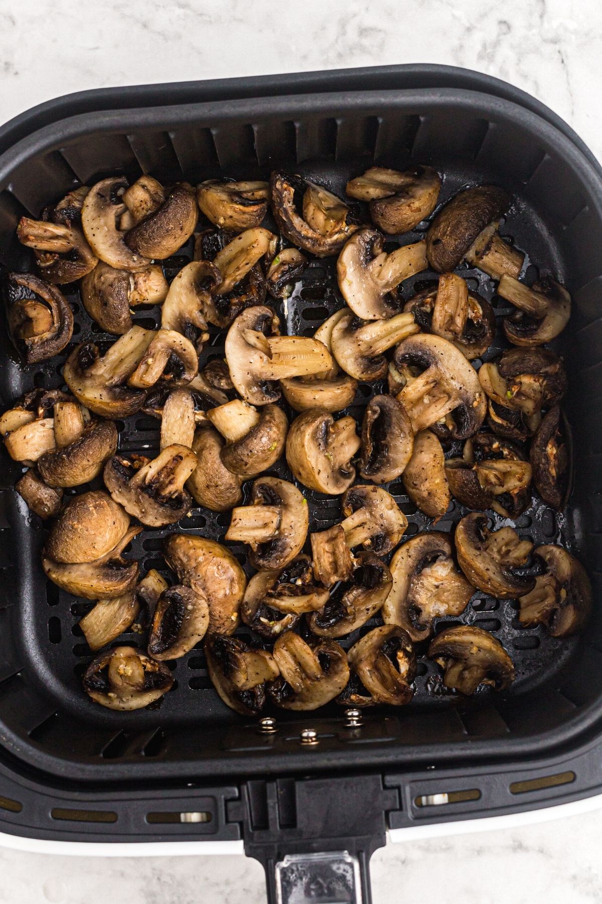 Juicy cooked mushrooms in the air fryer basket.
