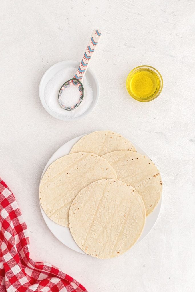 Corn tortillas, olive oil and salt on a white stone table