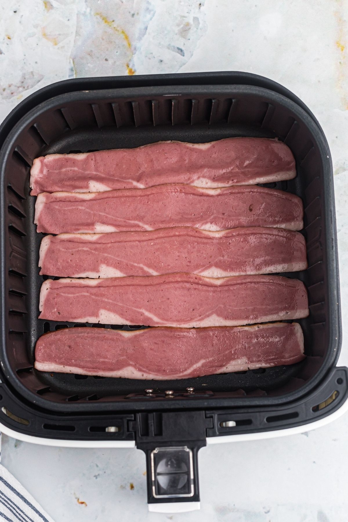 Uncooked turkey bacon in the air fryer basket.