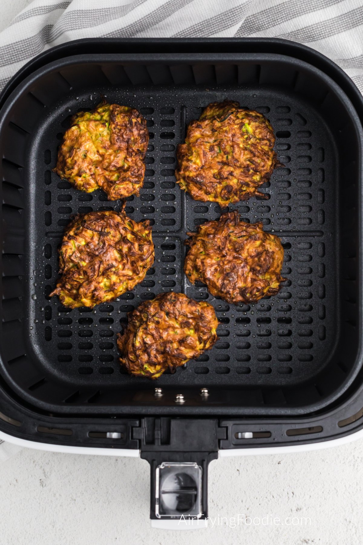 Fried zucchini fritters in the basket of the air fryer.