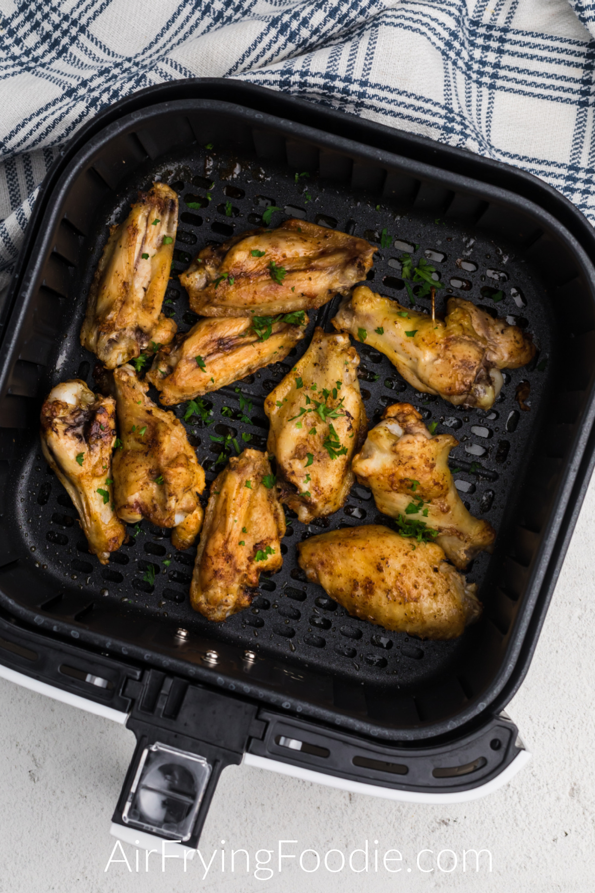 Seasoned frozen chicken wings in air fryer basket.