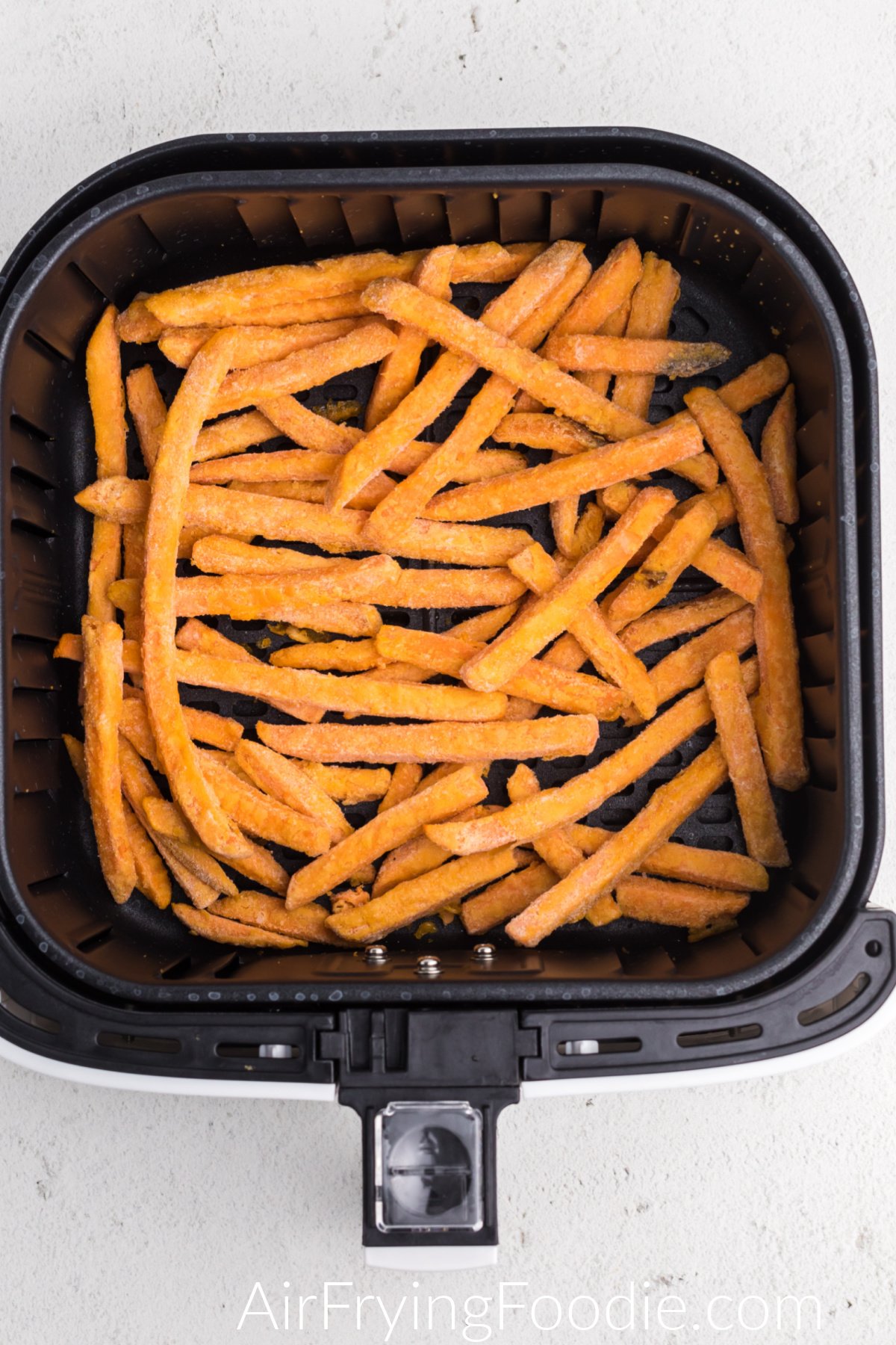 Frozen Sweet potato fries in the basket of the air fryer.