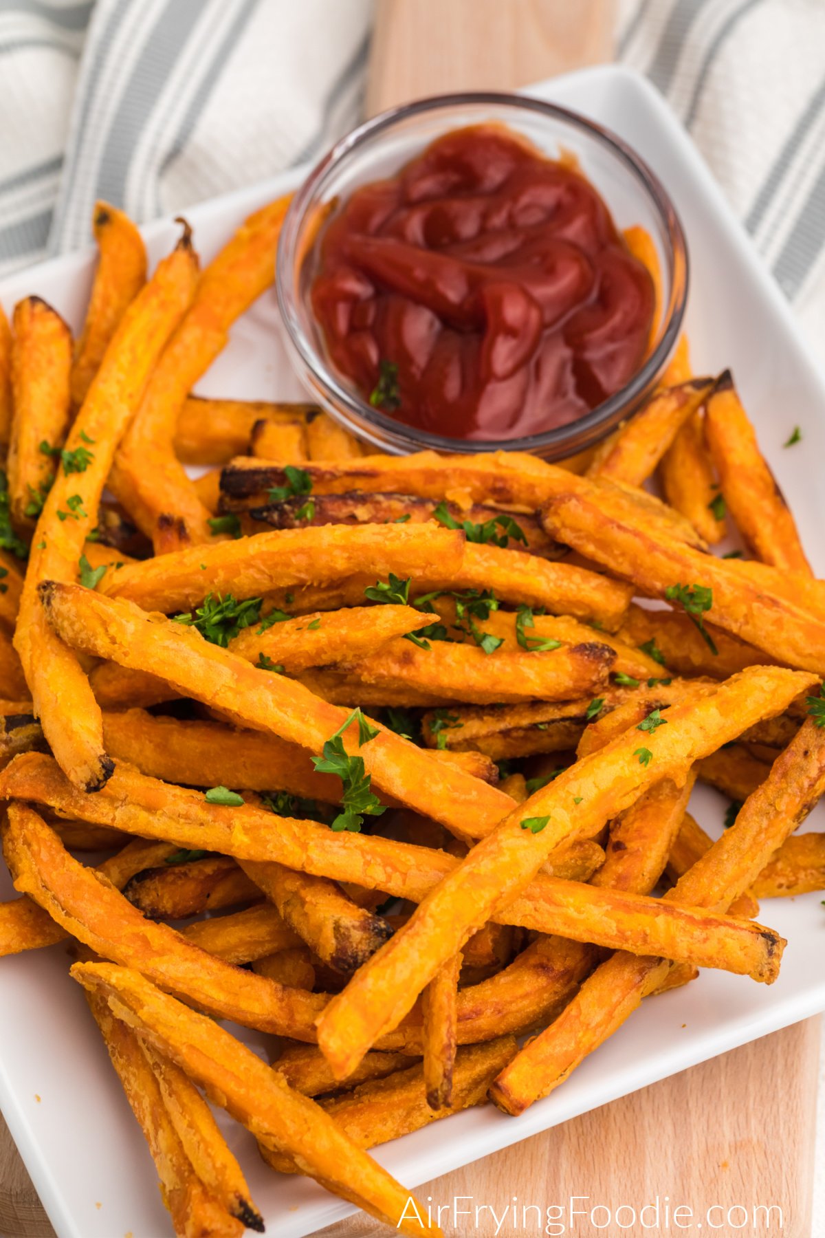 Plate full of cooked sweet potato fries with a side of ketchup.