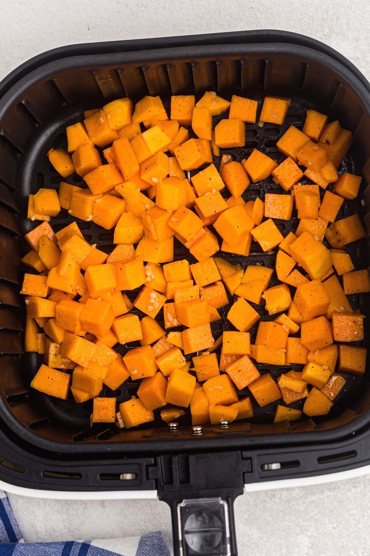 Orange squash but into cubes and seasoned in the air fryer basket.