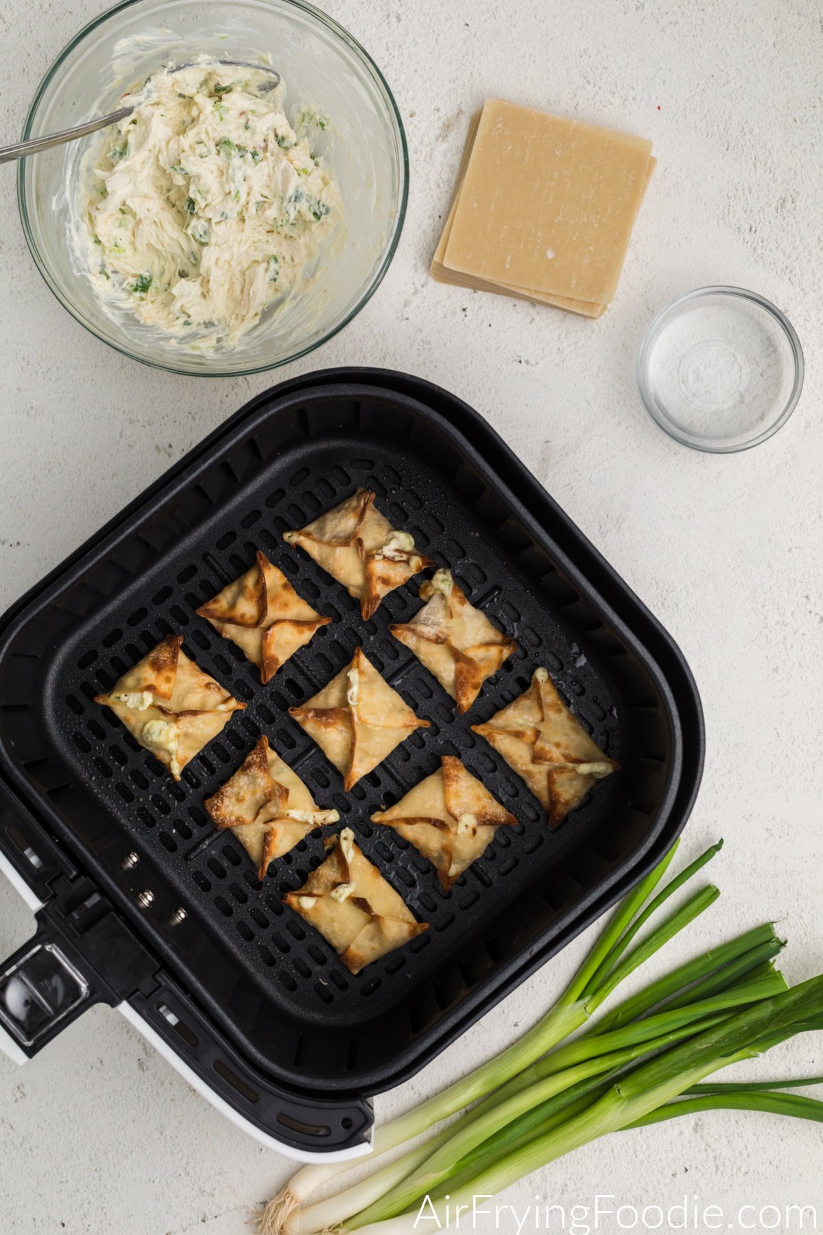 Golden brown air fried crab rangoon in the basket of the air fryer. 