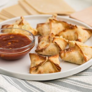 Air Fryer Crab Rangoon on a white plate with dipping sauce on the side.