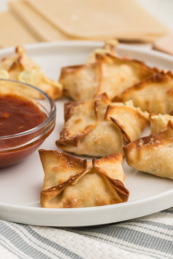 Air Fryer Crab Rangoon on a white plate with dipping sauce on the side.