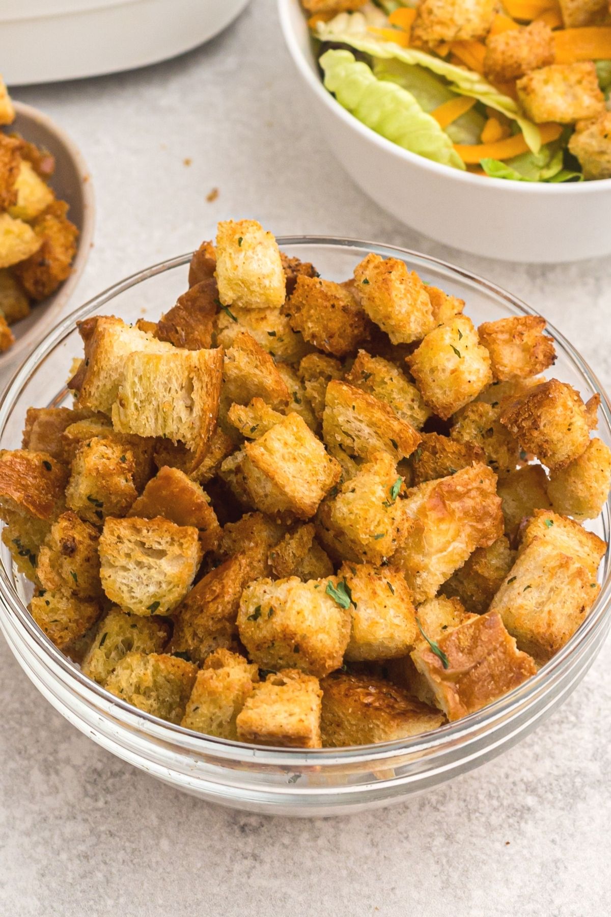 Golden crispy croutons in a clear glass bowl after being cooked in the air fryer. 
