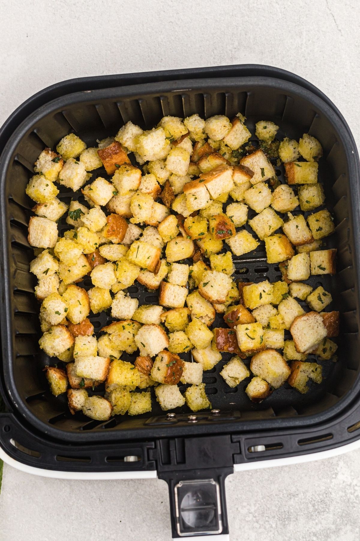 bread cubes coated in olive oil and seasoned in an air fryer basket