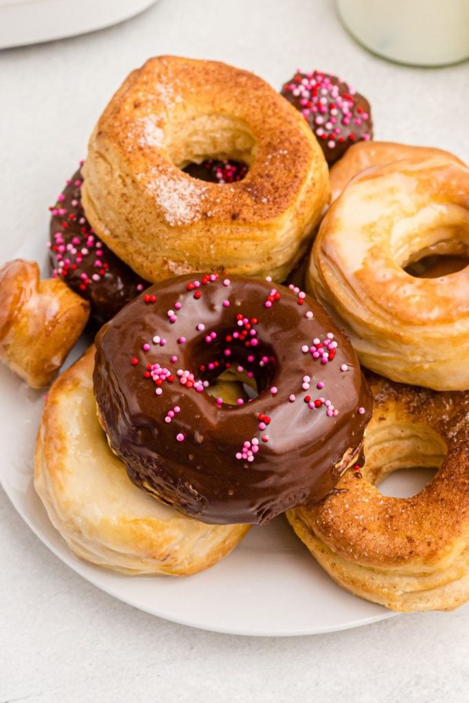 Golden donuts frosted with sprinkles and sugar, on a white plate