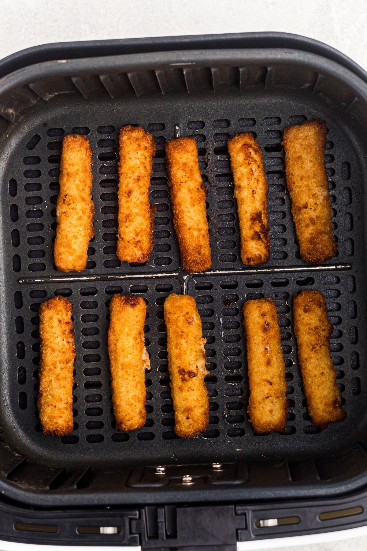 golden fried fish sticks in an air fryer basket